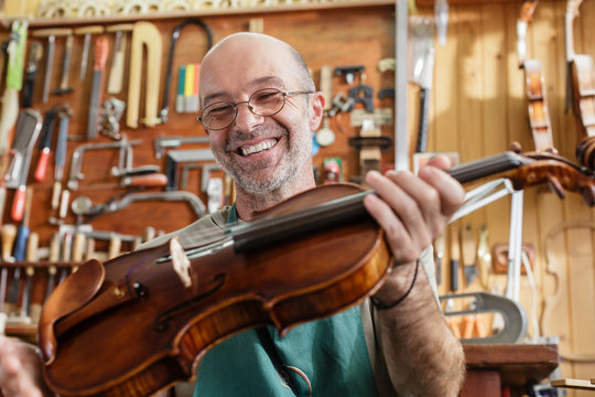 Violin maker checking finished instrument to his satisfaction