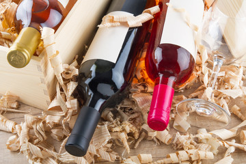 Assorted closed wine bottles lying on straw and wooden box