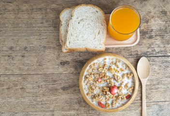 Bowl of breakfast muesli with oat and wheat flakes mixed with dried fruit and nuts in a woodden  bowl for a healthy nutritious meal.Served with wholewheat bread and fresh orange juice.