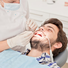 Obraz na płótnie Canvas young happy man and woman in a dental examination at dentist