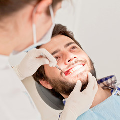 Obraz na płótnie Canvas young happy man and woman in a dental examination at dentist