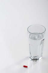 Glass of water and pills isolated on white