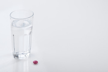 Glass of water and pills isolated on white