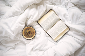 Cup of coffee and a book on bed - obrazy, fototapety, plakaty