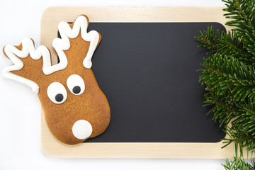 ein Rentier, eine Tafel und Tannenzweige