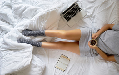 Girl reading book and drinking coffee on the bed