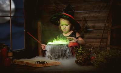 Halloween. child girl witch preparing  potion in cauldron