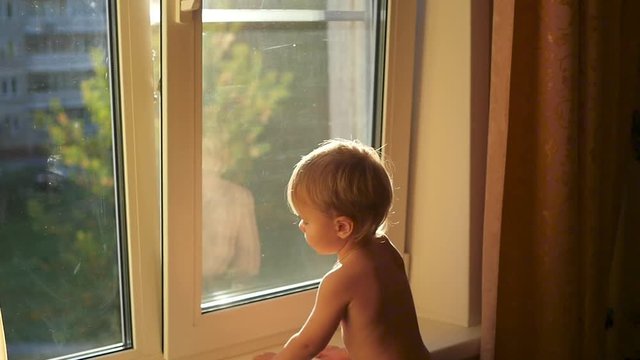 the child looks at the open window