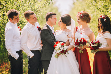 Bridesmaids have fun while wlking with bride in the park