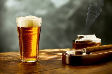 Single frothy beer with a burning cigar