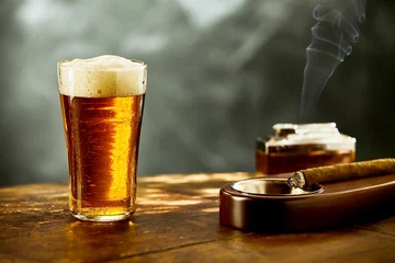 Gartenposter Einzelnes schaumiges Bier mit einer brennenden Zigarre © exclusive-design