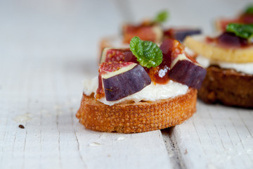 Bruschetta with goat cheese and figs on white wooden table