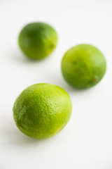 Fresh juicy limes on white wooden background close up