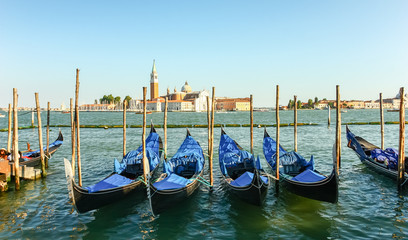 Fototapeta na wymiar Gondolas moored by Saint Mark square with San Giorgio di Maggior