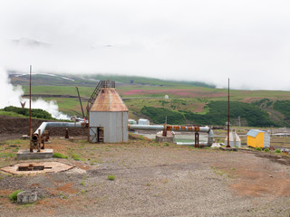 Geothermal station to heat homes and generate electricity stands at the foot smoking crater of the volcano Mutnovsky on Kamchatka in Russia against the background of a hill 
