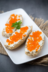 Red caviar on bread on white plate.