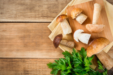 Boletus mushroms with parsley on cuting board on rustic wooden background