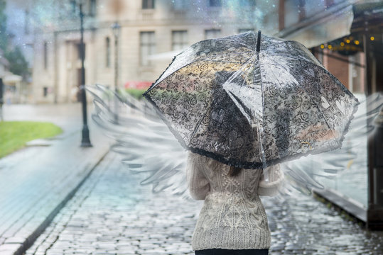 Woman with angel wings is the city under an umbrella