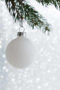 White decorative ball on the xmas tree on glitter bokeh background. Merry christmas card. Winter holiday theme. Happy New Year.