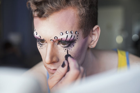 Young man applying dramatic eye makeup