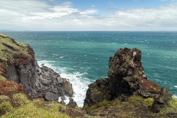 View of an ocean, rugged crag and steep cliff next to the Songaksan Mountain on Jeju Island in South Korea.
