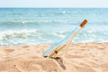 Fototapeta na wymiar Paper message SOS in a bottle on the tropical island beach at the seashore