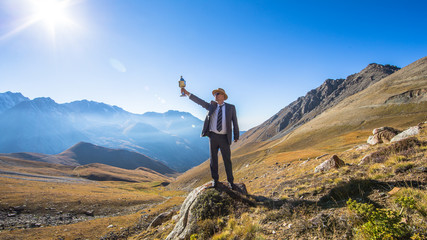 a man in a suit with a sports cup, mountain panorama, summer