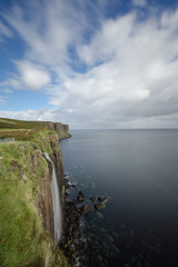 Beautiful waterfall ends up in the sea. Scotland&acute;s coastline with wonderful cliffs.
