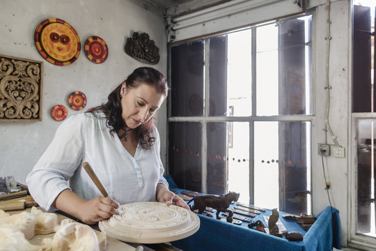 Woman whittling wood in wood carving art studio