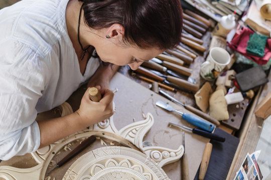 Woman working on wooden flourish carving with whittle