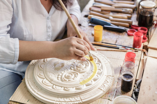 Woman in woodcarving studio painting wooden ornament