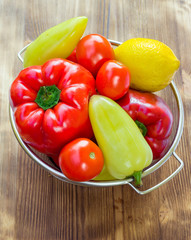 Vegetables in sieve bowl,  green and red peppers, tomatoes, lemo