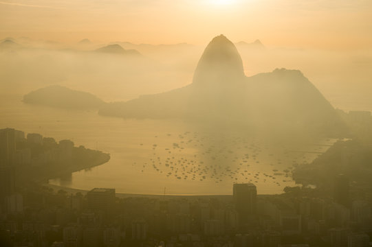 Misty golden sunrise skyline of Rio de Janeiro, Brazil with silhouette of Sugarloaf Mountain and Guanabara Bay