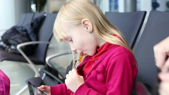 Child girl sucking sweets on wooden stick.