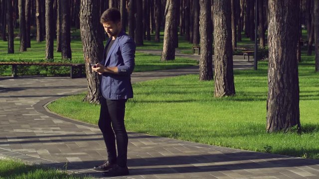 Young man and woman on a date in summer or spring season. Casual guy waiting for girl check message on the mobile phone. Businessman looking on the smartphone than coming female. Joyful meeting