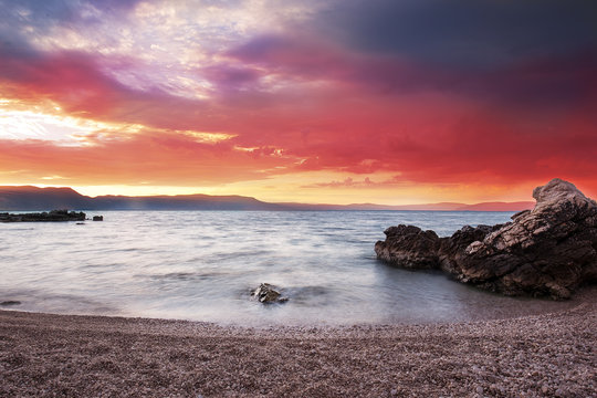 Sunrise with the red sky and clear turquoise ocean over the beach, Adriatic see, Istria, Croatia