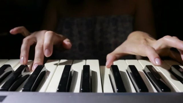 Woman hand playing a MIDI controller keyboard synthesizer close up.