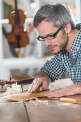 Craftman luthier working on the creation of a violin at workshop