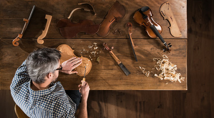 Top view. Artisan luthier working on the creation of a violin - obrazy, fototapety, plakaty