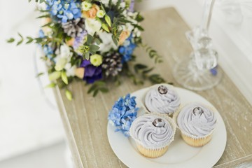Wedding decorations with bride's bouquet, candle and cupcakes. blue and serenity, close up shot of cupcake