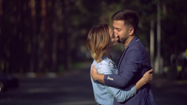 Portrait pair in love kissing and hugging in the city. Caucasian couple looking on each other with smile. Young blissful family outdoors wearing in casual dress enjoy life.