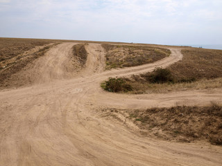 Пыльная грунтовая дорога ведет на вершину холма в Крыму