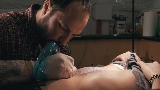 Tattoo master with beard making a tattoo of mandala pattern. Close up shot