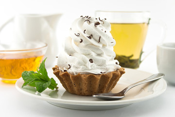 Birthday cupcake with mint on plate with cup of tea. 