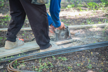Carpenter sawing wood board,carpenter chips from a circular saw at construction site