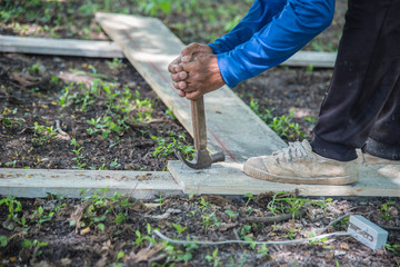 Worker working with a nail and a hammer in construction site