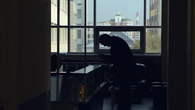 Man in a Dark Room Holding a Paper and Trying to Read a Text From it