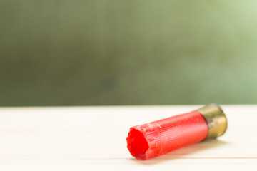 Still life antique clock placed on a wooden floor and a red shotgun shell with human skull on the back.