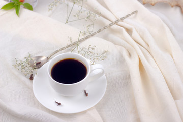 coffee in bed. cup of coffee with spices cloves on a white blanket