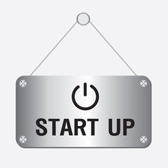 silver metallic start up sign hanging on the wall 